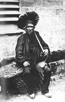 an old black and white photo of a man sitting on a bench holding a drum