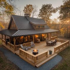 a large wooden deck with chairs on it next to a house in the woods at sunset