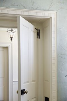 an open door in a room with blue wallpaper and white trim on the walls