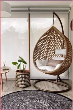 a hanging chair in the corner of a room with a rug and potted plant