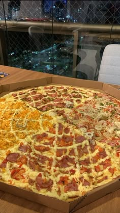 a large pizza sitting on top of a wooden table next to a glass window at night