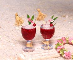 two glasses filled with liquid sitting on top of a wooden board next to flowers and grass