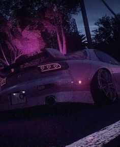 a car parked on the side of a road at night with its headlights turned purple