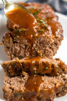 meatloaf with gravy being spooned over it on a white plate