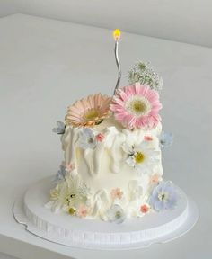 a white cake with flowers and a single candle