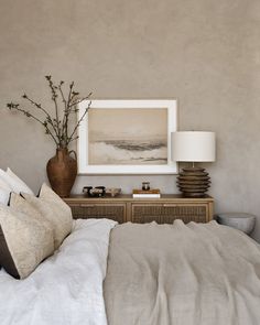 a bedroom with a bed, nightstand and painting on the wall