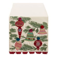 a table runner with ornaments on it and pine branches in the foreground, against a white background