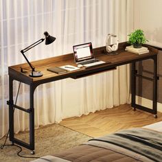 a laptop computer sitting on top of a wooden desk next to a lamp and window