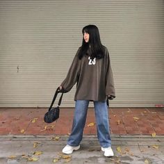 a woman is standing on the sidewalk with her handbag