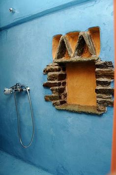 a bathroom with blue walls and a brick window in the wall next to a shower head