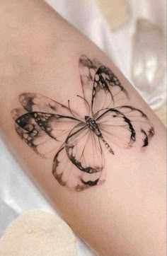 a woman's arm with a black and white butterfly tattoo on the left forearm