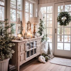 a christmas scene with candles and wreaths on the sideboard in front of large windows