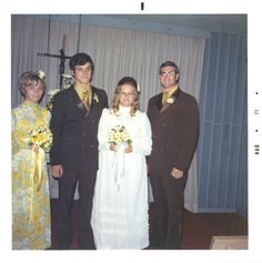 a group of people standing next to each other in front of a cross and curtains