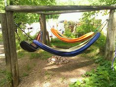 a hammock hanging from a wooden structure in the woods with trees and grass