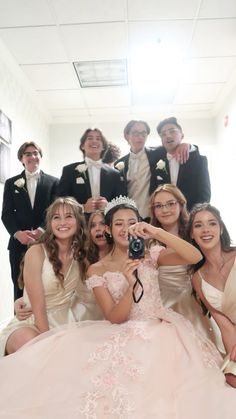 a group of people in formal wear posing for a photo with one woman holding a camera