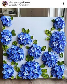 blue flowers are painted on a white canvas