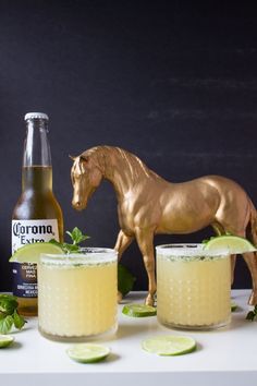 a horse statue next to two glasses filled with lemonade, lime and ginger ale