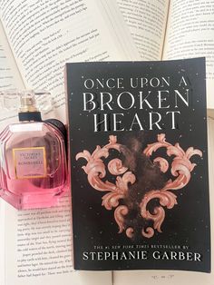 an open book next to a bottle of perfume