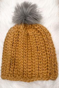 a knitted hat with a grey pom - pom on top