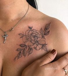 a woman's chest with a rose and cross tattoo on her left side shoulder