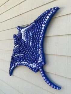 a blue and white piece of art on the side of a house that looks like a fish