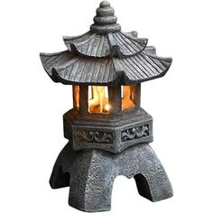 a small lantern with two lit candles in it on top of a stone stand,