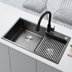 a stainless steel kitchen sink with black faucet and drainer in the middle