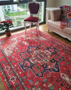 a red rug with an ornate design in front of a window