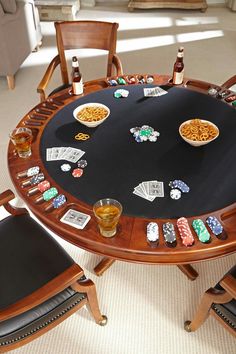 a black table topped with lots of cards and chips next to two chairs filled with drinks