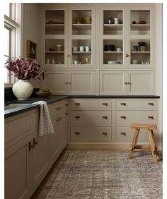 a kitchen with white cabinets and an area rug in front of the counter top that has a wooden step stool next to it