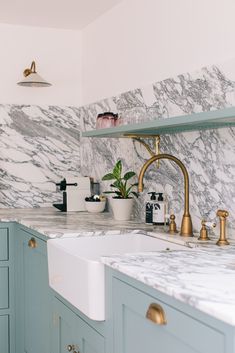 a kitchen with marble counter tops and gold faucets on the sink's side