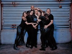 a group of people standing next to each other in front of a garage door with their arms around one another