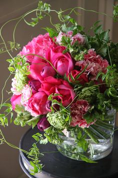 a vase filled with pink and red flowers on top of a black table next to a window