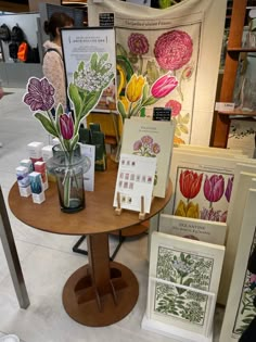 a table with cards and vases on it in a room filled with posters, flowers and other items