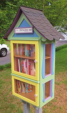 a colorful book shelf with books on it in front of a tree and grass area