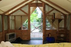 the inside of a tent with a bed, television and window to another room in it