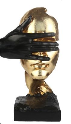 a gold and black statue with a hand on it's head