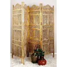 an ornate wooden room divider with two vases on the floor next to it