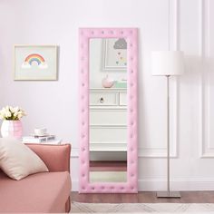 a pink mirror sitting on top of a wooden floor next to a couch and table