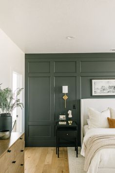 a bedroom with dark green walls and white bedding