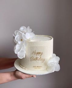 a white hat with flowers on it is being held by a woman's hand