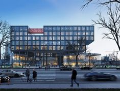 people are walking on the sidewalk in front of a large glass building with many windows