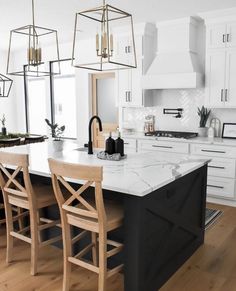 a large kitchen with white cabinets and black island in the center is surrounded by wooden chairs