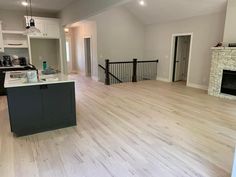 an empty kitchen and living room in a house with white walls, hardwood floors and black appliances