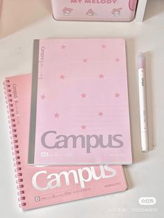 a pink notebook sitting on top of a white table next to a pen and pencil