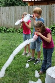 three children are playing with water hoses in the yard