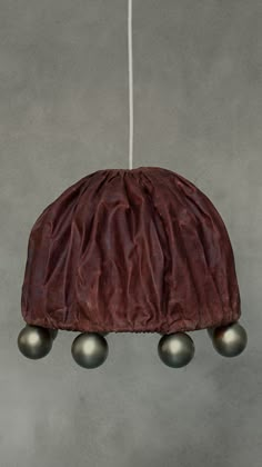 a brown hat hanging from a string with three balls attached to the top of it