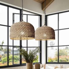 two lamps hanging from the ceiling above a table with pillows and vases on it