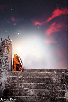 a man sitting on top of some steps under a sky filled with stars and the moon