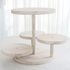 three circular wooden tables sitting next to each other on a tablecloth covered floor with curtains in the background